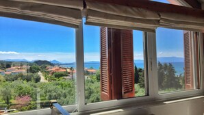 A room with a view of a coastal landscape, including houses and mountains. - Margarita Apartments (Preveza)