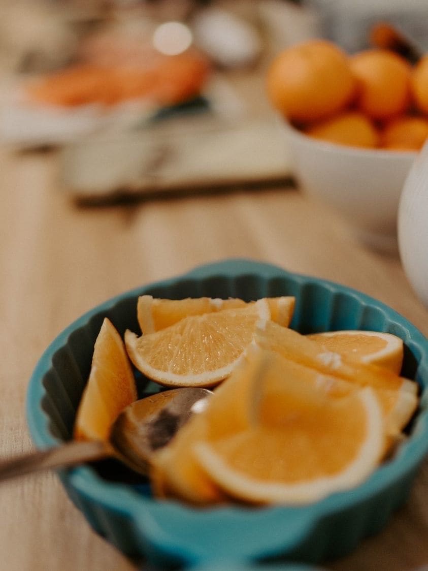 A bowl of sliced oranges on a table.