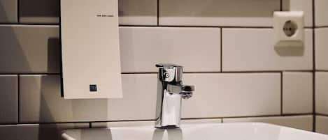 A bathroom with a white sink, a mirror, and a paper towel dispenser.