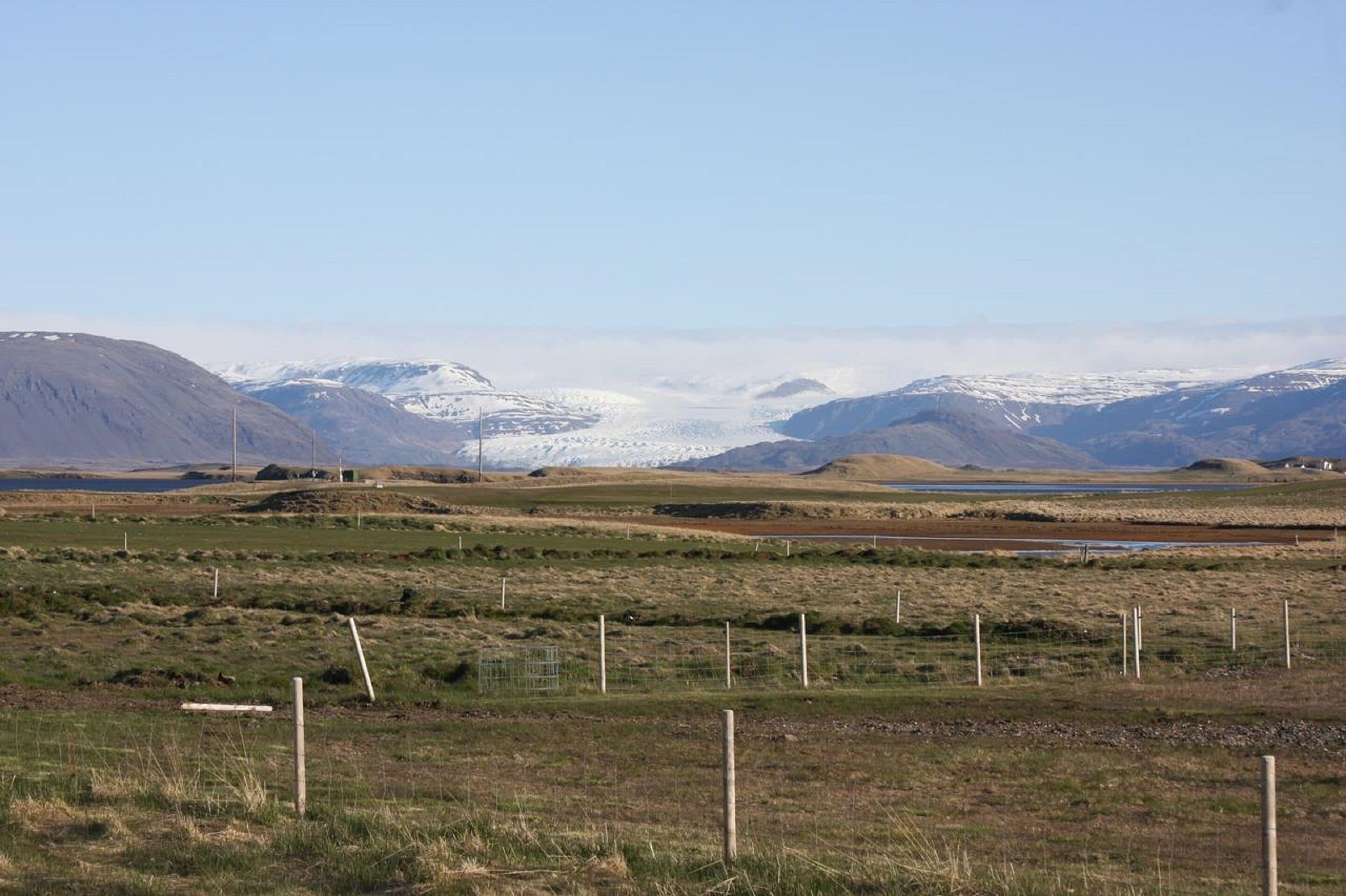 A wide-open landscape with rolling hills and a distant snow-capped mountain range.