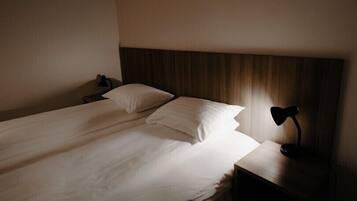Un lit simple avec du linge de lit blanc dans une chambre d’hôtel.