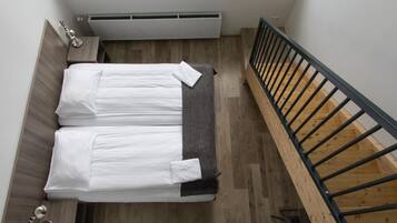 Un dormitorio con cama, radiador, suelo de madera y una escalera.