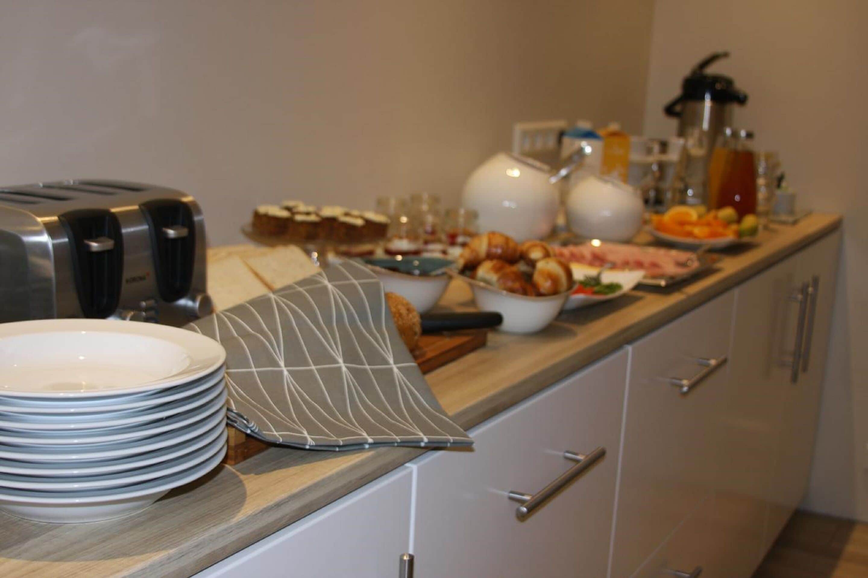 Una mesa de buffet con platos, tazones y un tostador.