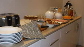 Una mesa de buffet con platos, tazones y un tostador.
