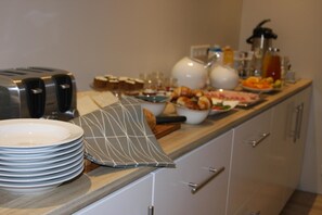 A buffet setup with plates, bowls, and a toaster.