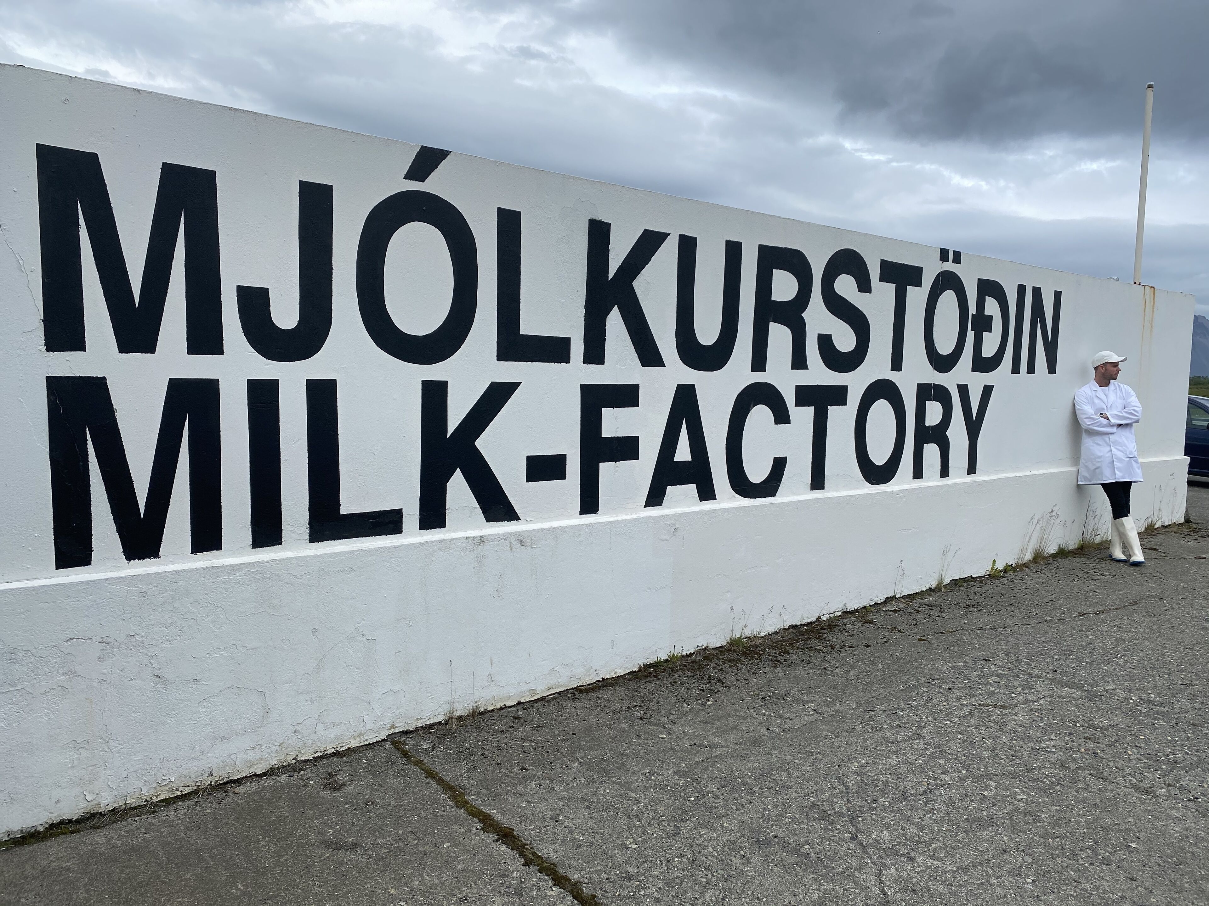 A sign for a milk factory with a person standing beside it.