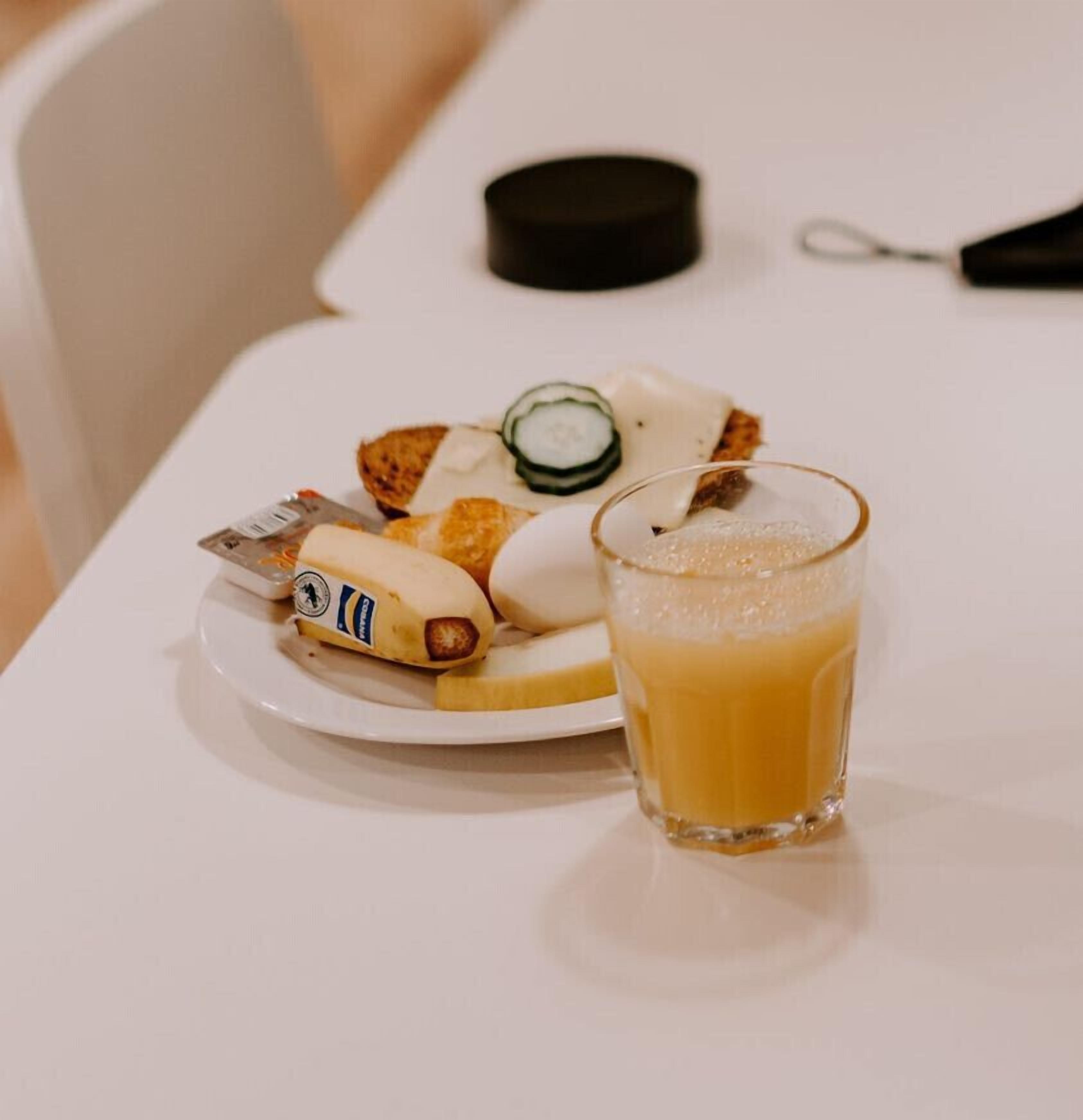 A plate with a banana, a slice of cheese, and a cucumber on a white table.