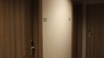 Een gang met houten deuren, genummerd 103 en 102.
