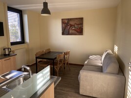 Una cocina compacta con zona de comedor, un sofá y un cuadro en la pared.