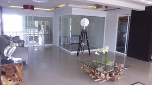 Un intérieur moderne avec une table basse en verre, un trépied et un vase rempli de fleurs.