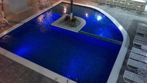 Une piscine avec un îlot central et des chaises longues disposées tout autour.