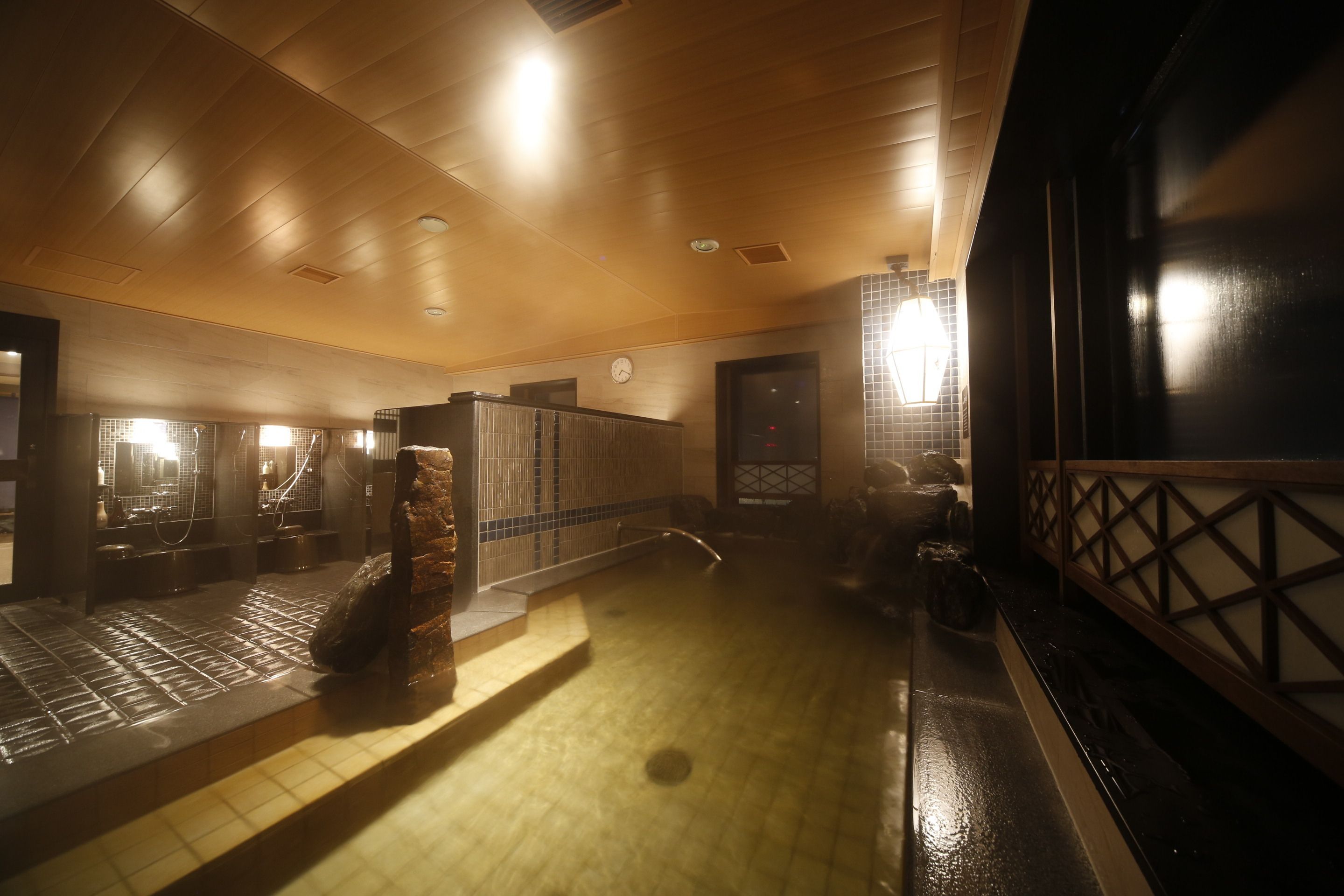 A public restroom with a wooden ceiling, tiled walls, and a tiled floor.