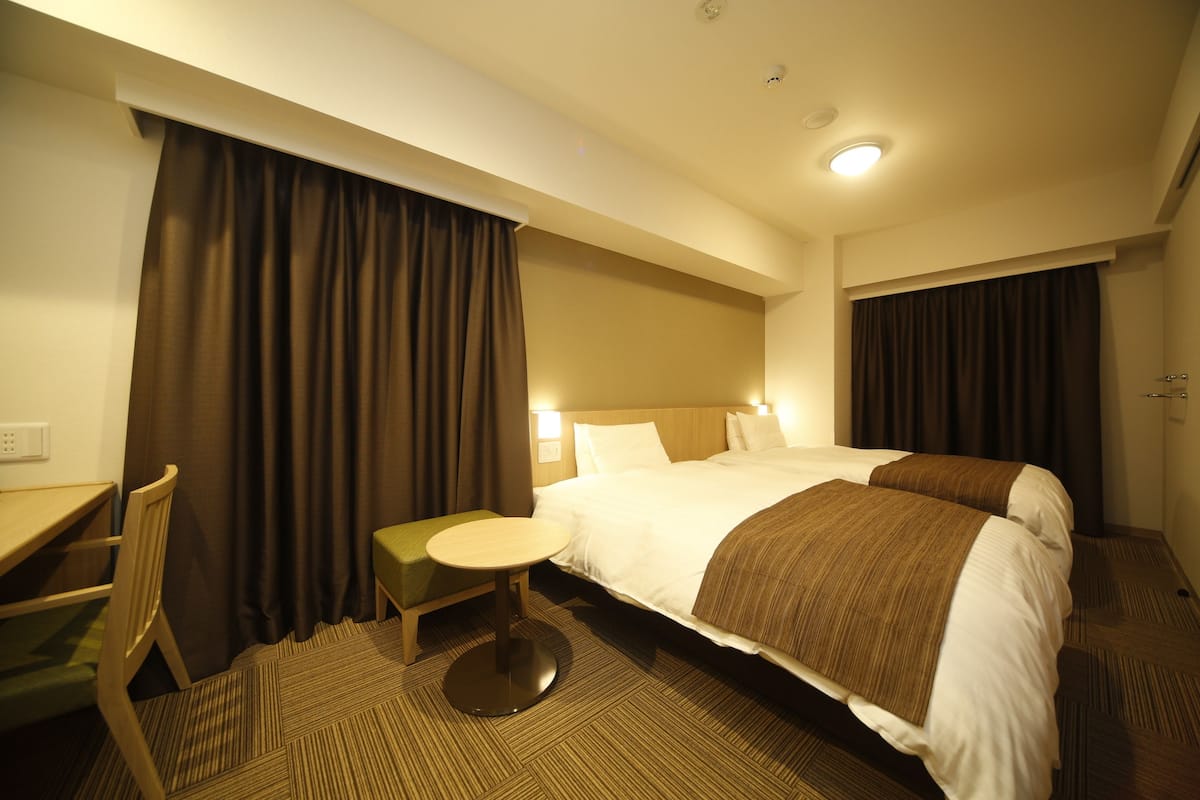 Ein Hotelzimmer mit Bett, Schreibtisch, Stuhl und einem kleinen Tisch.