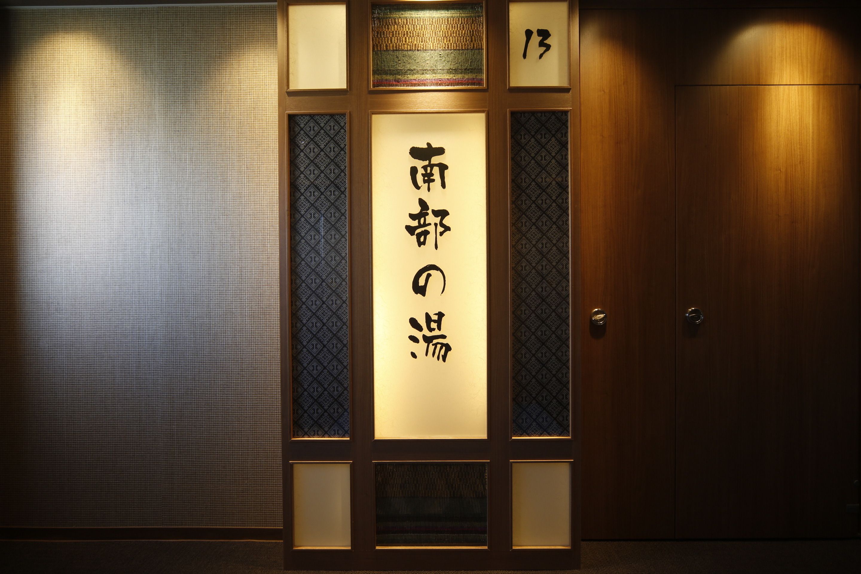 Una habitación japonesa tradicional con una puerta corredera, un celosía de papel y un panel de madera con caracteres japoneses.