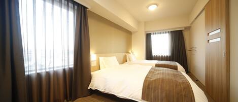A hotel room with a large bed, a wardrobe, and a window with curtains.