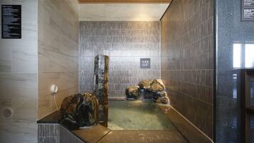 A spa area with a hot tub, tiled walls, and a wooden ceiling.