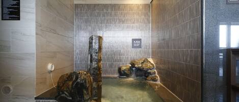A spa area with a hot tub, tiled walls, and a wooden ceiling.