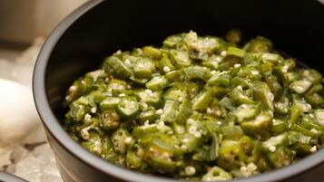 A bowl of sliced green vegetables, possibly okra, with seeds.