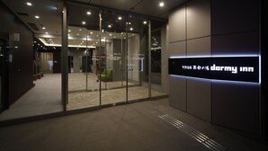 Une entrée d’hôtel moderne avec une porte en verre, un comptoir d’accueil et une enseigne indiquant « Darmy Inn ».