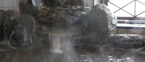 Un área de aguas termales con rocas grandes y una cascada.