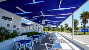 An outdoor dining area with white tables and chairs, covered by blue canopies, and a sign indicating a restaurant. - Futura Club Torre Rinalda (Lecce)