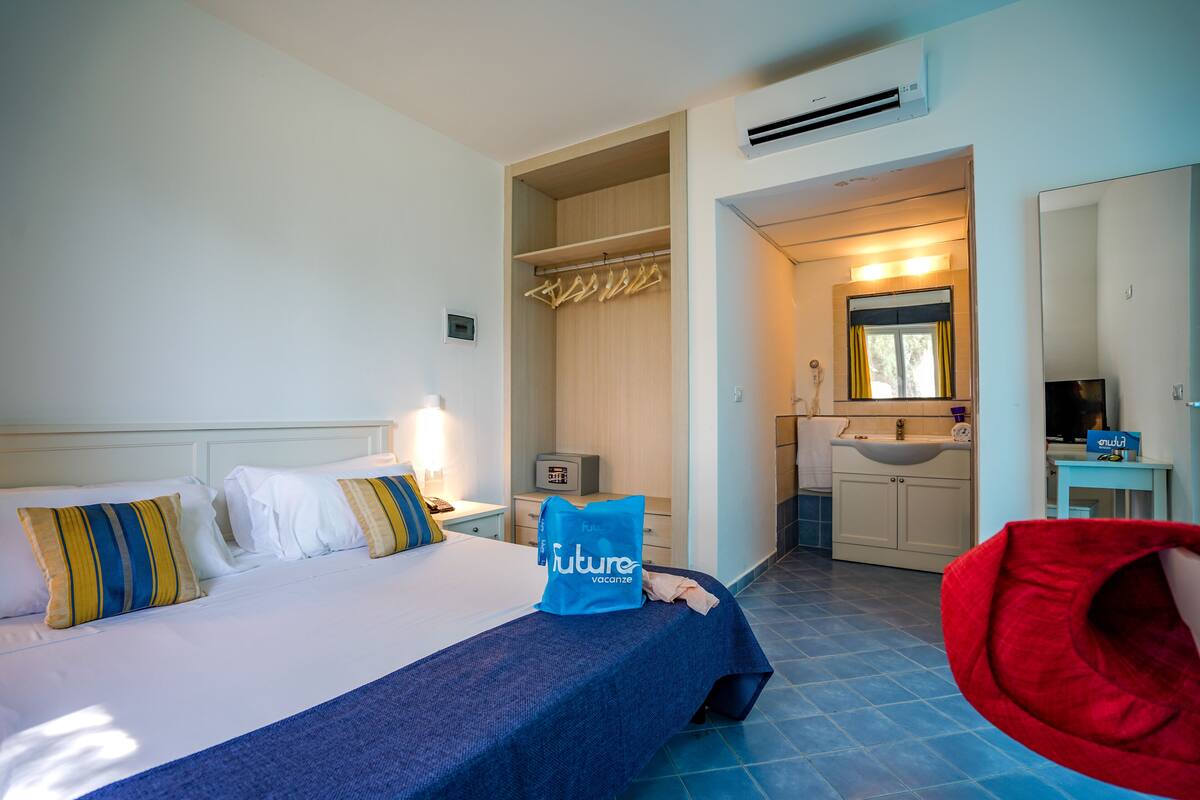 A hotel room with a bed, a bathroom, and a red chair.