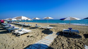 A beach with rows of sun loungers and umbrellas, a clear blue sky, and the ocean in the background. - Futura Club Torre Rinalda (Lecce)
