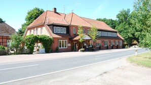 A two-story brick building with a red-tiled roof, a central entrance, and a small porch area. - Misselhorner Hof (Südheide)