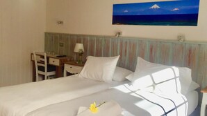 A hotel room with a bed, a desk, and a painting of a mountain on the wall. - Hotel Frutillar (Frutillar)