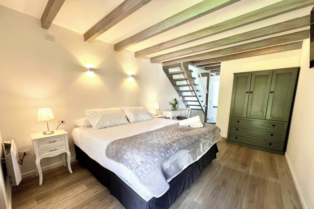 A bedroom with a bed, nightstand, lamp, and a green wardrobe.