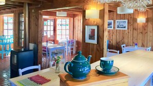A wooden interior with a dining area, a table with a teapot and cups, and a wall with framed pictures. - Hotel Frutillar (Frutillar)