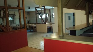 A spacious living area with a dining table and chairs, a kitchen area, and a staircase. - Gästehaus Vienenburg (Goslar)