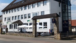 A large hotel with multiple floors, a prominent entrance with a glass door, and a rooftop with solar panels. - Gästehaus Vienenburg (Goslar)
