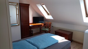 A bedroom with a bed, a desk with a chair, a television, and a radiator. - Gästehaus Vienenburg (Goslar)