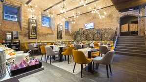 Um restaurante com paredes de tijolo, iluminação moderna e diferentes opções de assentos.