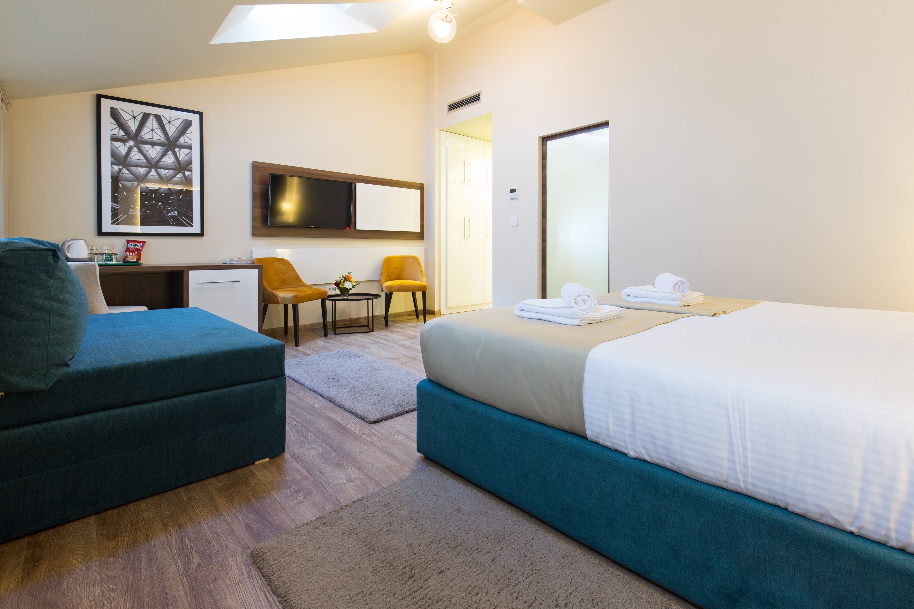 A hotel room with a bed, a desk, a chair, a sofa, and a TV.