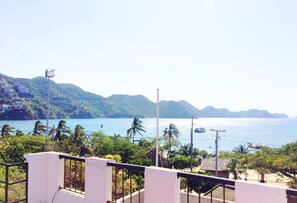Vista costeira com céu claro, uma praia e uma montanha ao fundo.