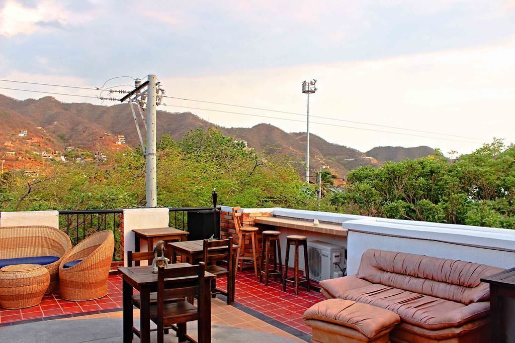 Um terraço no telhado com móveis de vime, um bar e vista para uma paisagem montanhosa.