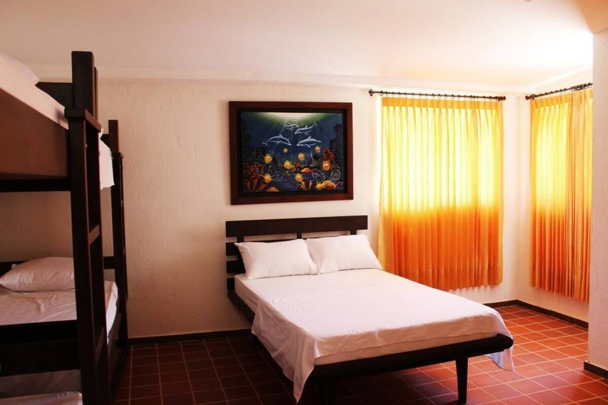 A room with a bunk bed, a single bed, and a painting on the wall.