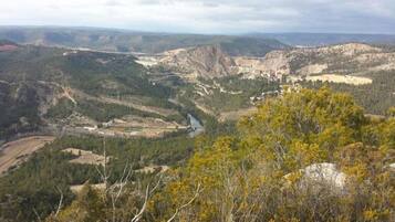 A mountainous landscape with a river, forested areas, and a small settlement.