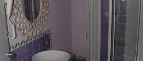 Une salle de bain comprenant un meuble-lavabo, un lavabo, des toilettes et un espace douche.