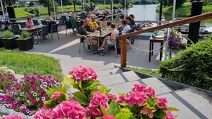 An outdoor dining area with tables and chairs, surrounded by potted plants and flowers. - Hotel Restaurant Bootshaus (Achim)