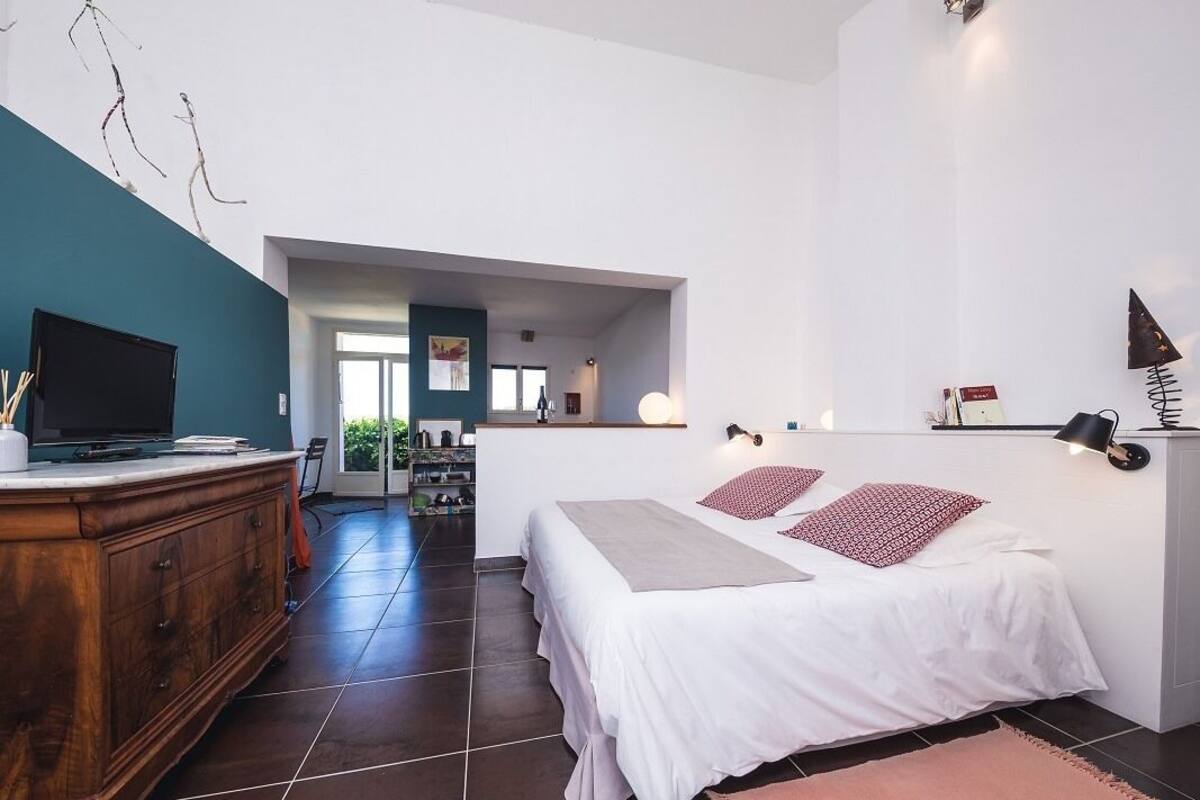 Une chambre à coucher comprenant un lit, des tables de chevet, une commode et un téléviseur.