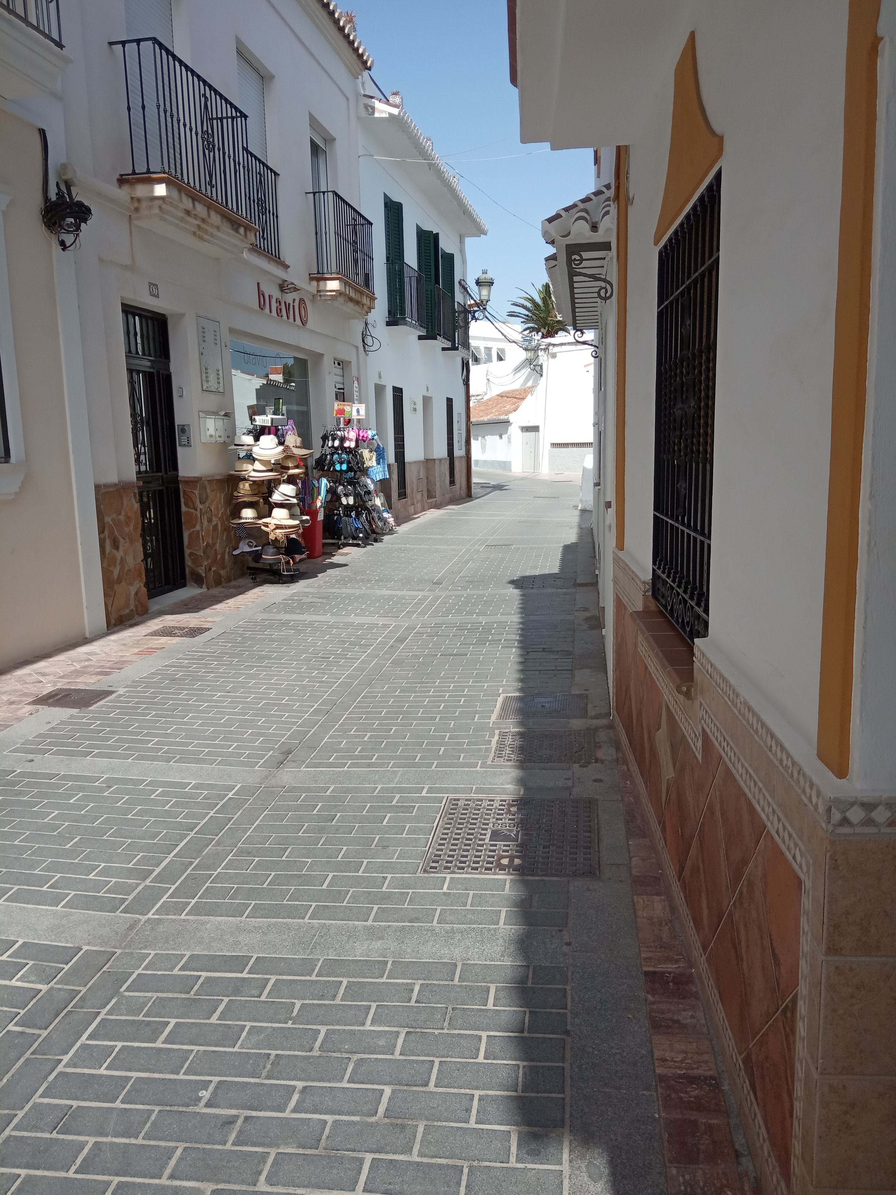A narrow street with a shop selling hats and accessories on the left.