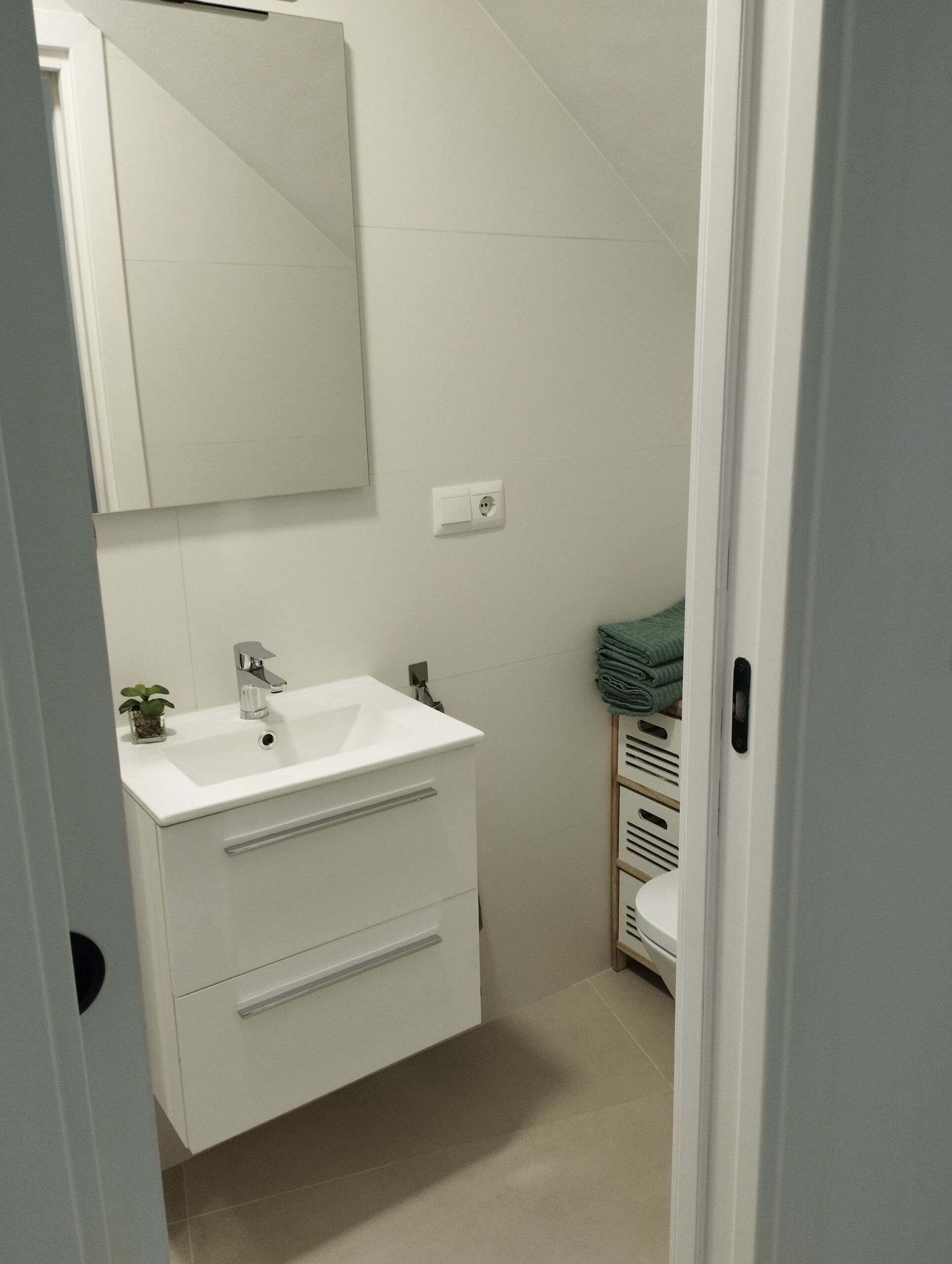 A bathroom with a white sink, a mirror, and a towel rack.