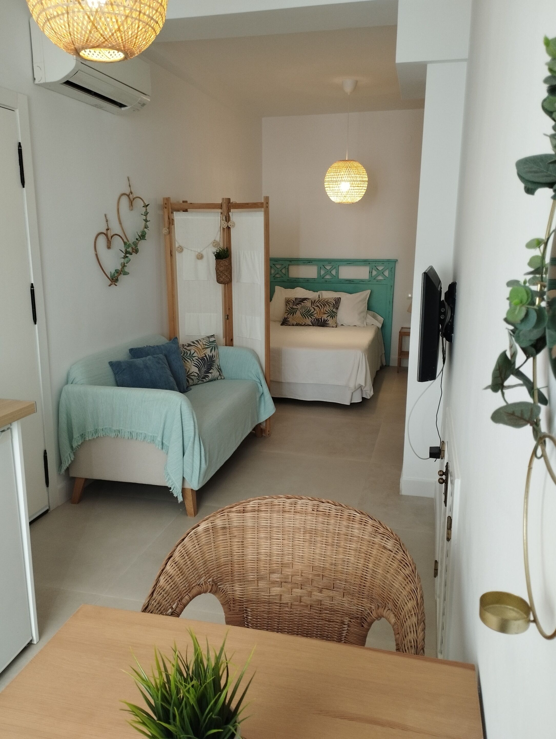 Una habitación acogedora con cama, una silla, una mesa y una lámpara colgante.