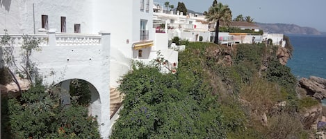 A coastal building with white walls and a balcony overlooking the sea.