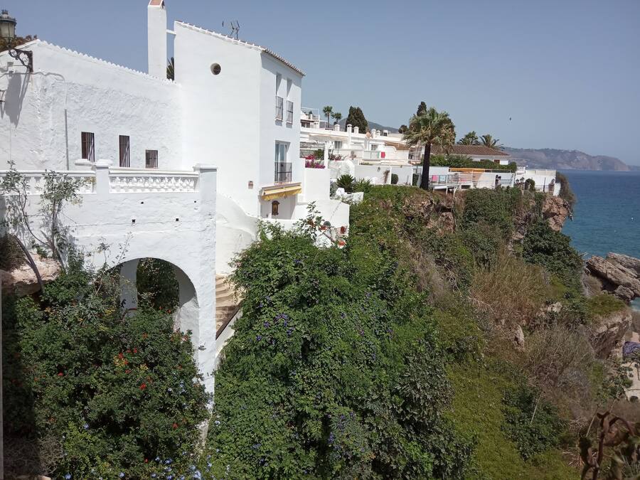 Un edificio costero con paredes blancas y un balcón con vistas al mar.