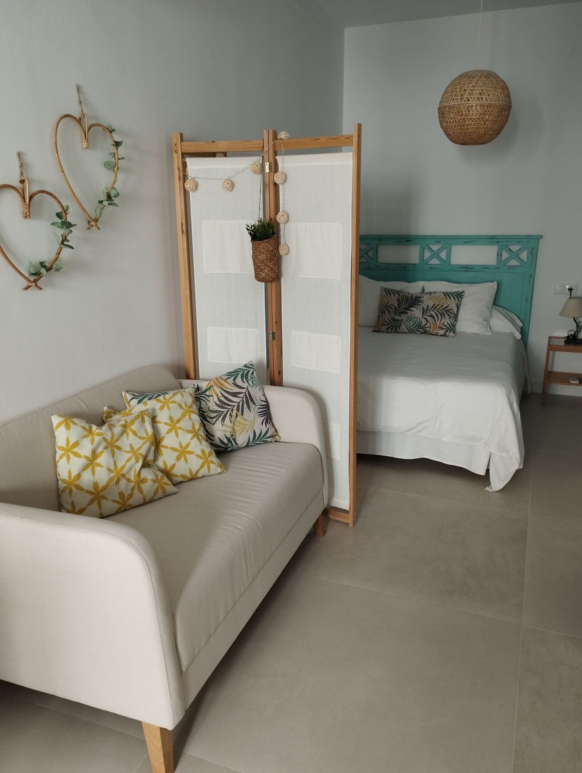 A bedroom with a bed, a sofa, and a wall-mounted basket.