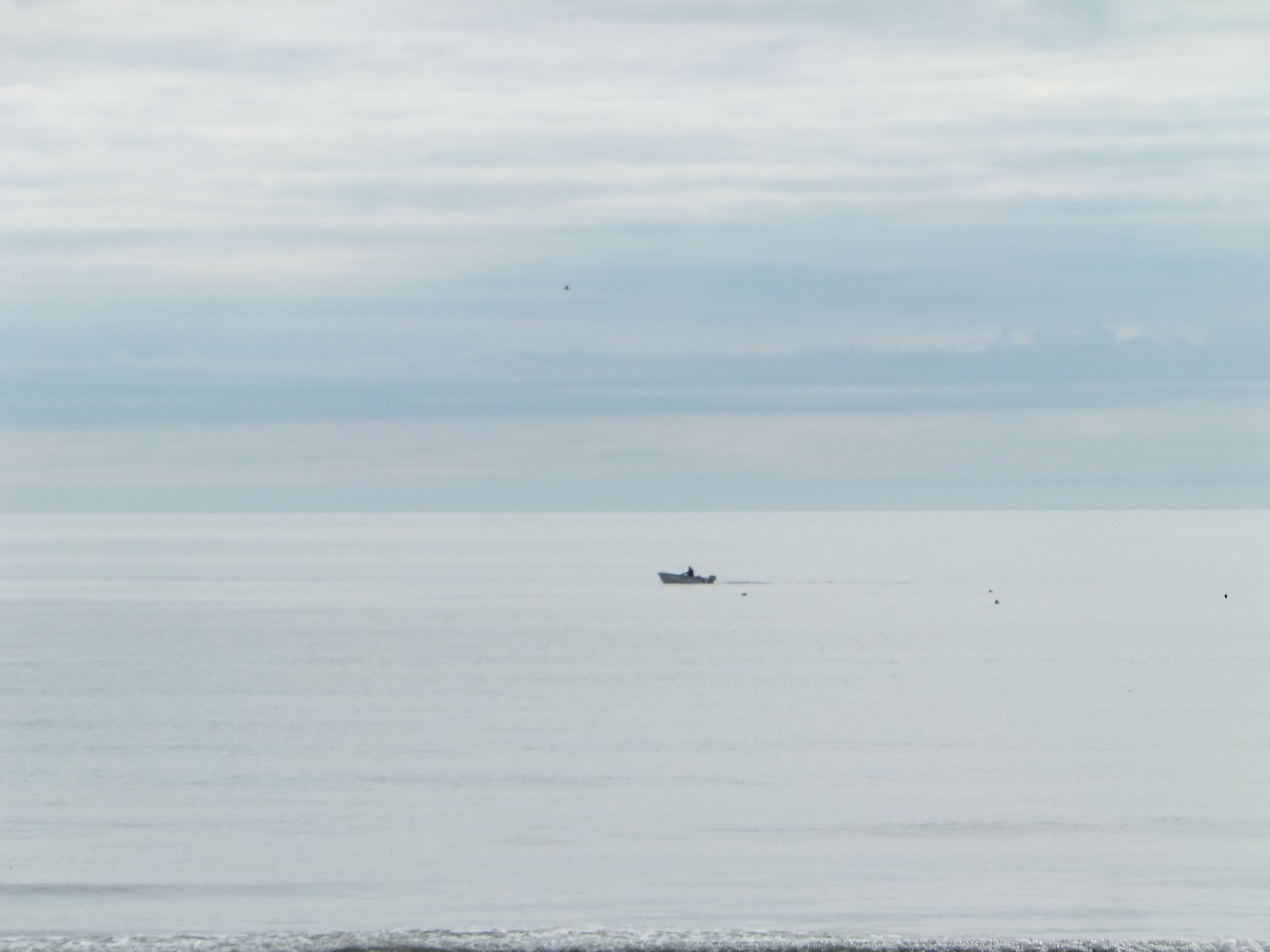 A calm sea with a small boat in the distance.